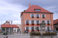 Interkommunales Bürgerzentrum Hofheim - 3-geschossiges Haus mit Walmdach, Sprossenfenstern,  Fensterläden; links weitere Bebauung; im Vordergrund Freifläche mit Brunnen