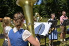 Eine Bläsergruppe spielt im Schatten eines Baumes vor der Häuserkulisse des Freilandmuseums.