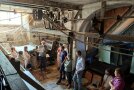 Personen stehen in einem historischen Gebäude. Es ist eine Mühle.