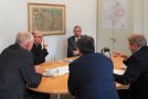 Der Bischof hat das Wort ergriffen und hat am ovalen Konferenztisch vier aufmerksame Zuhörer. Seine Gestik mit erhobenem Zeigefinger lässt eine wichtige Aussage erwarten.