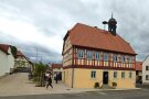 Ein schmuckes Fachwerkhaus, das historische Rathaus von Holzhausen, steht frei auf einem neu angelegten Dorfplatz.