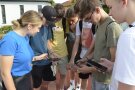 Schüler lesen auf ihren Smartphones ihre aktuellen GPS-Koordinaten aus.