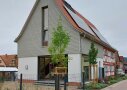 Für den Neubauteil des Hauses hat man sich für eine graue Holzvertäfelung entschieden. Im unteren Bereich des Hauses wurden große Fensterfronten, die für viel Licht in den Räumen sorgen, eingebaut. Das Grundstück wird durch Pflanzbeete, Bäumen und einem Zaun zum Gehweg abgegrenzt.