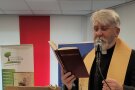 Ein Mann in Priesterkleidung – mit Stehkragen und Stola – liest ein Gebet aus dem Benediktionale vor.