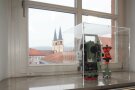 Ein historisches Messgerät steht auf einem Fensterbrett mit Blick zur Würzburger „Schottenkirche“.
