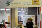 Blick auf den Messestand des Amtes für Ländliche Entwicklung Unterfranken. Die Standbesetzung trägt ein schwarzes T-Shirt mit dem Logo der Ländlichen Entwicklung in Bayern und einen für Außeneinsätze gut geeigneten Strohhut.