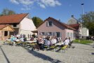 Dorfbewohner nehmen Platz auf dem Dorfplatz für die Segnung des Dorfgemeinschaftshauses.
