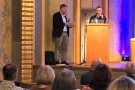 Immobilienentwickler Christian Skrodzki am Rednerpult wird von Moderator Dr. Rudolf Neumaier interviewt.