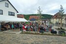Eine Blaskapelle mit jungen Musikerinnen und Musikern sitzt auf Stühlen vor einem Festzelt und spielt für die Gäste auf.
