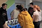 Ein Jungenteam kickert gegen ein Mädchenteam. Den Spieltisch umringen weitere Jugendliche.