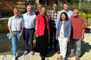 Drei Frauen und fünf Herren mit freudestrahlenden Gesichtern. Sie haben sich vor dem Naturteich zum Gruppenfoto aufgereiht.