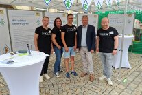 Ein Bild zeigt Personen, die einen Stand betreuen.