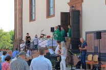 Gottesdienst unter freiem Himmel. Zur Rechten am Kirchenportal die Geistlichkeit, zur Linken die Gläubigen.