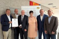 Gruppenbild mit mehreren Personen. Sie verleihen eine Urkunde.