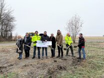 Mehrere Personen mit Schaufeln stehen zusammen. Sie beginnen symbolisch ein Bauprojekt.