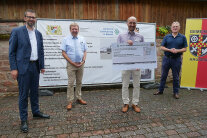 Amtsleiter Jürgen Eisentraut übergibt den Scheck an Bürgermeister Michael Bein, mit dabei sind Landrat Jens Marco Scherf und Landtagsabgeordneter Berthold Rüth