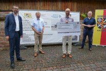 Amtsleiter Jürgen Eisentraut übergibt den Scheck an Bürgermeister Michael Bein, mit dabei sind Landrat Jens Marco Scherf und Landtagsabgeordneter Berthold Rüth
