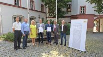 Mehrere Personen stehen vor der Kamera. Sie zeichneten zwei Menschen aus.