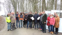 Eine Gruppe von Personen steht zusammen. Sie starten symbolisch mit einer Waldmaßnahme. 