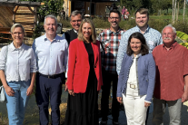 Drei Frauen und fünf Herren mit freudestrahlenden Gesichtern. Sie haben sich vor dem Naturteich zum Gruppenfoto aufgereiht.