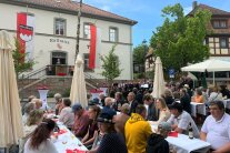 Vollbesetzte Bänke an weiß gedeckten Tischen auf dem Platz vor dem Casteller Rathaus.