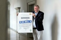 Amtsleiter Jürgen Eisentraut hält einen Förderbescheid hoch.