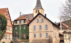 Fachwerkgebäude im fränkischen Stil, eine Kirche im Hintergrund