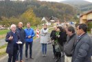 Allianzmanager Uwe Schmidt erläutert die Planung des neuen Bahn-Radwegs „RHÖX“. Der Allianzmanager steht auf der Straße vor den Teilnehmern mit einem Manuskript in der Hand. Im Hintergrund Wohnhäuser und ein herbstlich bewaldeter Bergrücken.