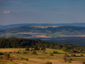 Rhönlandschaft mit drei Höhenzügen eines Mittelgebirges, viel Wald und reich strukturierter Landschaft