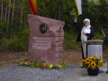 Pastoralreferent Rainer Zöller steht am Rednerpult rechts neben dem Gedenkstein und nimmt die Segnung vor.
