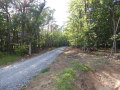 Ein neuer Weg mit Wasserrückhaltung: Bildmitte ein Schotterweg im Wald, rechts daneben ein Wassergraben