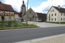 Ortsdurchfahrt Wettringen mit Straßenrandgestaltung und Grünstreifen. Im Abschluss St. Kilians-Platz mit Kirche im Hintergrund.