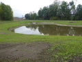 Das Rückhaltebecken Maulensee in Rüdenhausen nach der Fertigstellung, eingesäumt von Hecken und Rasenbegrünung.