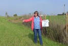 Miriam Glanz vom Planungsbüro Glanz steht vor einer landschaftspflegerischen Struktur und erklärt anhand einer Karte die umgesetzte Maßnahme