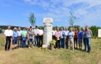 Einweihung des Flurdenkmals in Nordheim vor der Rhön. Die anwesenden Bürger stehen links und rechts neben dem neuen Flurdenkmal. Ganz links Joachim Mair, der Vorsitzende des Vorstands der Teilnehmergemeinschaft Nordheim vor der Rhön 5. Das Flurdenkmal ist aus Stein gefertigt und symbolisiert Ähren, Baum und Flureinteilung