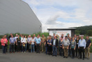 Gruppenfoto mit den Teilnehmern des Netzwerktreffens der bayerischen Öko-Modellregionen 2017 bei der Besichtigung des Ökobetriebs Remlinger Rüben. Links eine große Lagerhalle, im Hintergrund das Firmenschild Remlinger Rüben.